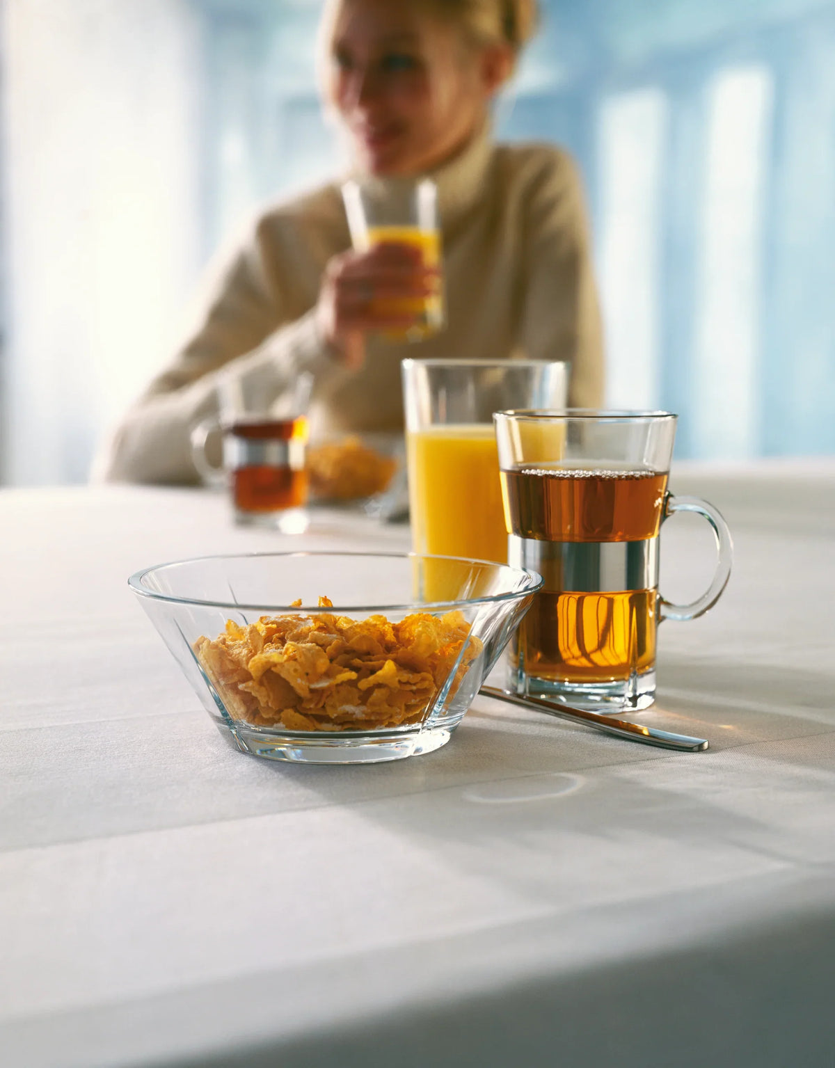 ROSENDAHL Grand Cru caféglas med te og juice på et dækket bord ved siden af en skål cornflakes.
