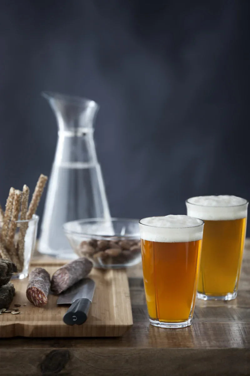 To ROSENDAHL Grand Cru glas med øl, serveret med pølse, nødder og grissini på et skærebræt.