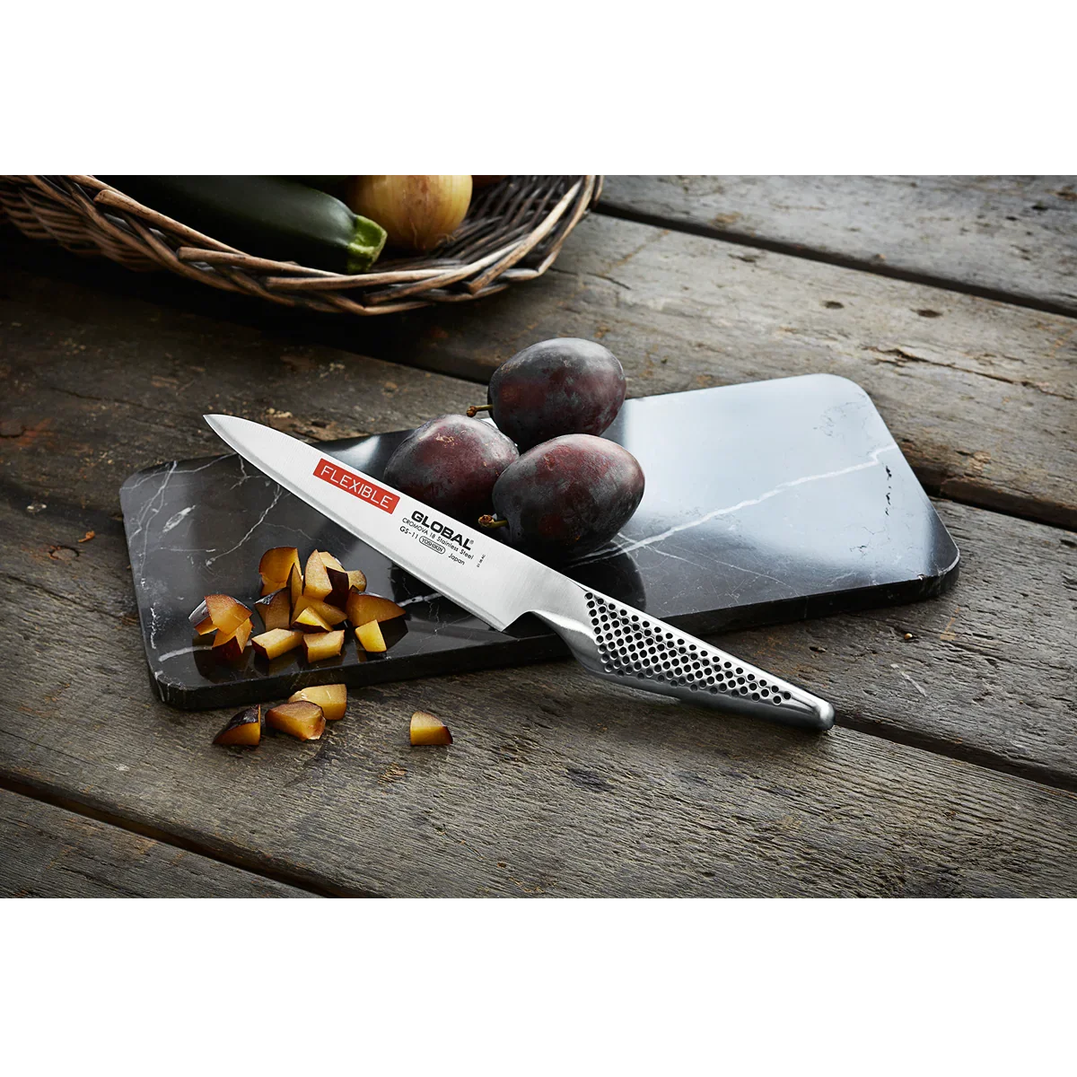 GLOBAL universalkniv GS-11 på skærebræt med blommer og frugtstykker