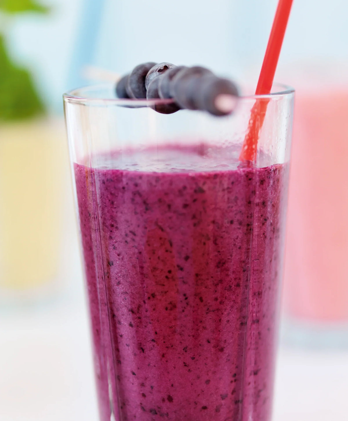 Lilla blåbær smoothie i et ROSENDAHL Grand Cru caféglas med et rødt sugerør.