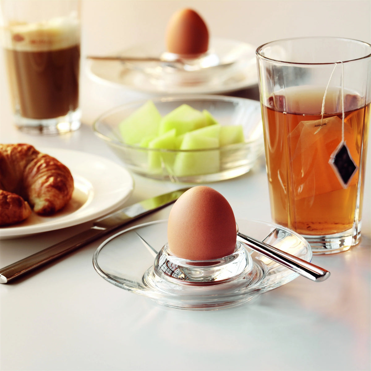 Morgenmad med ROSENDAHL glas, blødkogt æg, croissant og frugt på et hvidt bord