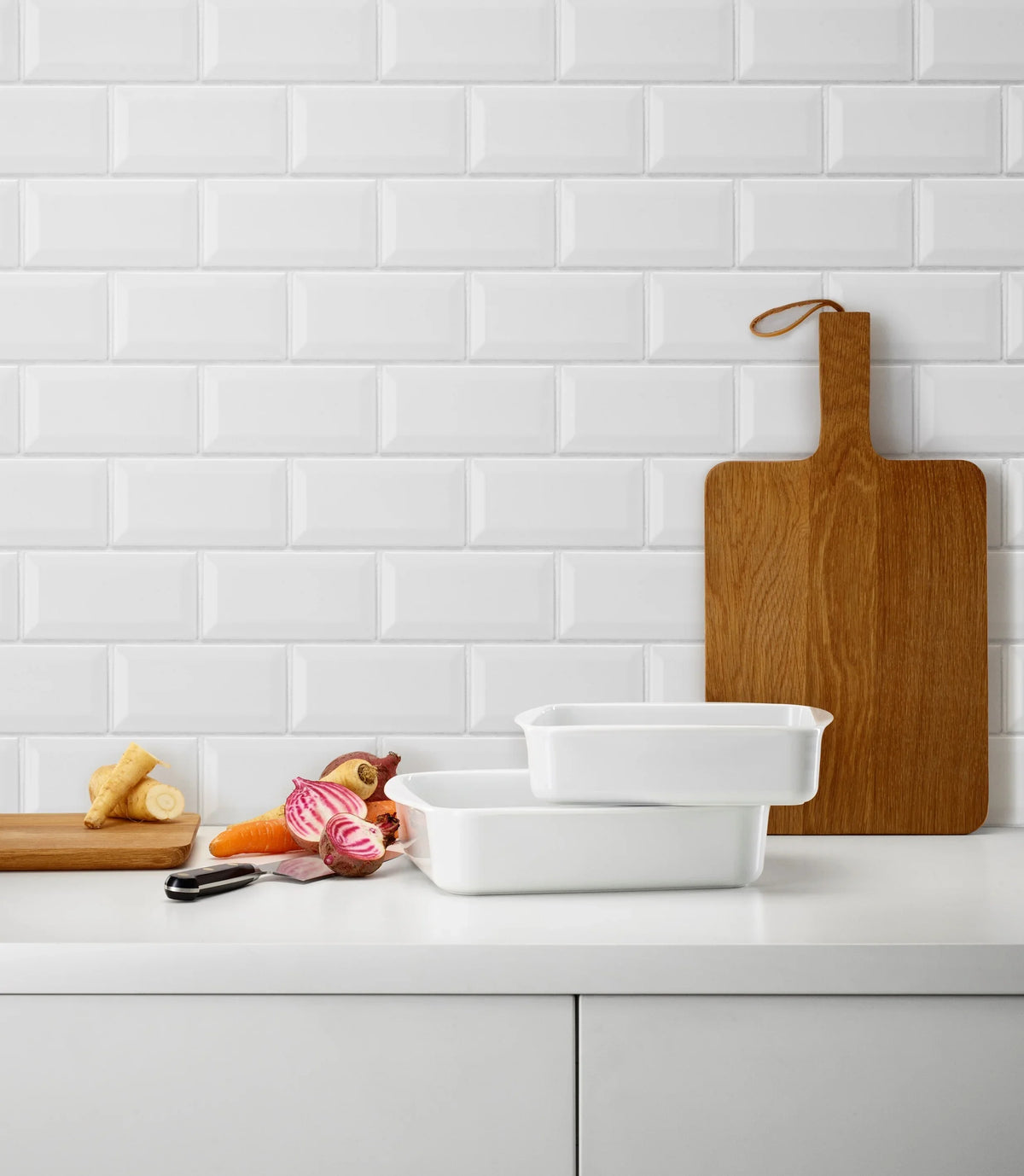 Hvidt EVA TRIO Legio lasagnefad i porcelæn med grøntsager og skærebræt på køkkenbord