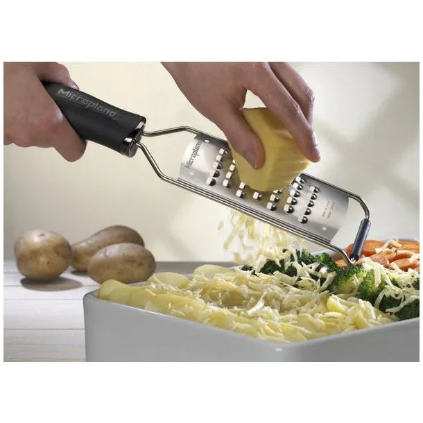 Microplane ekstra grov Gourmet rivejern der river kartofler i en hvid bageform